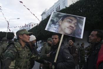 Un manifestante con una imagen de una de las víctimas de las protestas junto a un soldado. (Foto: STR)