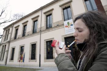 Una joven enciende un cigarrillo en el exterior del Parlamento vasco, donde ayer se aprobó la nueva ley. (Foto: A. R. DE HIERRO)