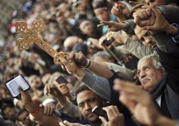 Un cristiano copto levanta una cruz y un libro religioso en una manifestación en El Cairo. (Foto: HANNIBAL HANSCHKE )