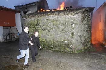 Un joven aleja a una mujer mayor del fuego, al lado de una de las 'palleiras' afectadas. (Foto: MIGUEL ANGEL)