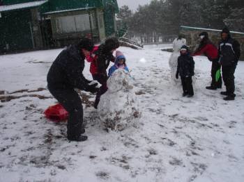 Mayores y niños construyen muñecos de nieve.