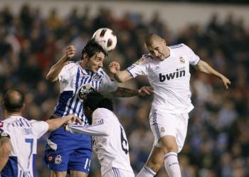 Benzema salta por un balón con Diego Colotto en el partido disputado el sábado en Riazor. (Foto: CABALAR)