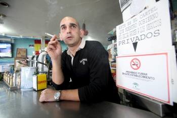 Rafael León, fumando en el interior de su establecimiento, el pasado día 9.  (Foto: RAFA ALCAIDE)