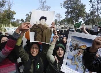 Estudiantes leales al líder libio, Muamar al Gadafi, portan carteles con su fotografía y gritan consignas contra las cadenas de noticias árabes Al Arabiya y Al Jazeera por publicar lo que consideran noticias falsas sobre la actual crisis que atraviesa Lib