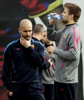 Guardiola, con gesto de preocupación junto a Piqué durante el entrenamiento del miércoles.? (Foto: a. estévez)
