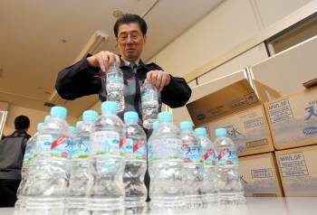 Un funcionario del Gobierno metropolitano de Tokio prepara botellas de agua para repartir a familias con bebés. (Foto: )