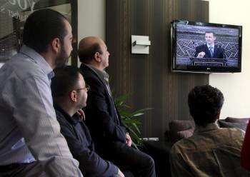 Sirios siguen por televisión el discurso del presidente sirio, Bachar al Asad, desde el Parlamento. (Foto: YOUSSEF BADAWI)