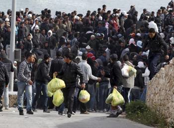  Inmigrantes procedentes del norte de África esperan la llegada del ferry que los trasladará a otros centro de Italia, en la isla de Lampedusa .