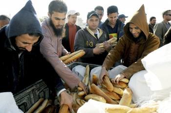  Rebeldes libios cogen barras de pan para ofrecérselas al pueblo de Ajdabiya, (Libia) .