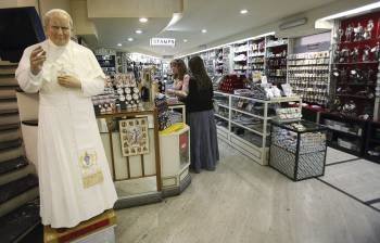  Una estatuda del Papa Juan Pablo II en una tienda, donde se venden souvenirs y tarjetas postales, cerca de la basílica de San Pedro, en la Ciudad del Vaticano.