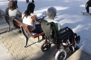 Una mujer discapacitada disfruta del buen tiempo en un parque, con una cuidadora. (Foto: MARCOS ATRIO)