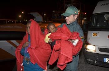 Un guardia civil ayuda a inmigrantes que llegaron en patera a Motril el pasado diciembre. (Foto: JOSÉ MIGUEL PÉREZ PAQUET)