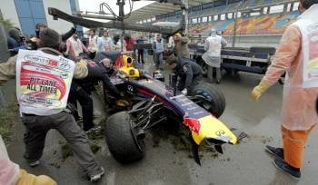 Trabajadores del circuito retiran el coche accidentado del piloto alemán de Red Bull, Sebastian Vettel. (Foto: TOLGA BOZOGLU)