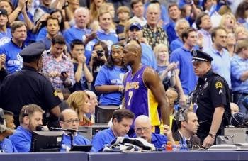 El jugador de los Lakers Lamar Odom sale escoltado de la cancha por la policía tras cometerle una falta a Dirk Nowitzki. (Foto: LARRY W. SMITH)