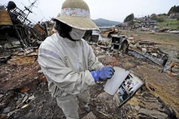 Una mujer con el álbum de fotos que encontró entre los escombros de su vivienda en Kesennuma. (Foto: FRANCK ROBICHON)
