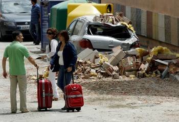 Vecinos de Lorca, con sus maletas, por una calle cubierta por los escombros. (Foto: JUAN CARLOS CÁRDENAS)