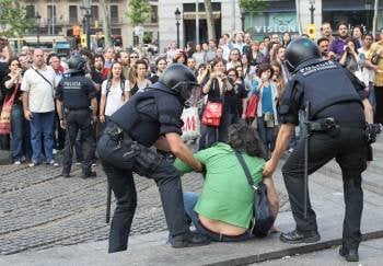 Dos mossos presionan a un 'indignado' a que abandone la Plaza de Cataluña, en Barcelona. (Foto: Toni Albir)