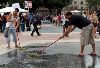 Dos jóvenes limpian la plaza de Cataluña, tomada de nuevo por los 'indignados'. (Foto: TONI ALBIR)
