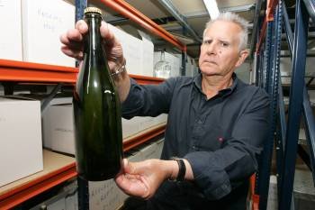 Un trabajador de la Estación de Viticultura e Enoloxía muestra una botella de vino espumoso. (Foto: MARCOS ATRIO)