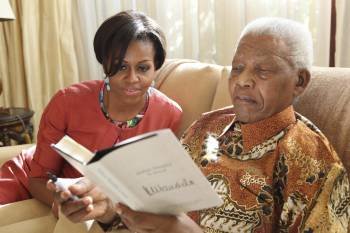 Michelle Obama (i), junto al ex presidente sudafricano Nelson Mandela, mientras ojean el libro 'Nelson Mandela by himself', en su residencia en Houghton.
