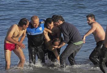 Agentes de la Policía Local, ayudados por civiles, sacan del mar el cuerpo del argelino fallecido.  (Foto: CABALAR)