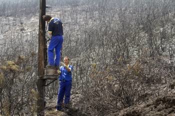 Operarios tratan de restablecer la comunicación telefónica en una zona afectada por el incendio en A Cañiza. (Foto: S. SAS)