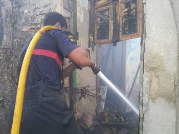Un bombero intenta sofocar el fuego que afectó ayer a una casa deshabitada en Pazos de San Clodio. (Foto: JAINER BARROS)
