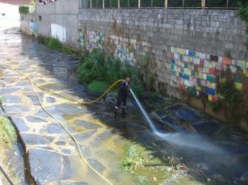 Un miembro del equipo de emergencias limpia el arroyo Cigüeño.