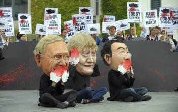 Tres activistas caricaturizan al ministro alemán de Exteriores Guido Westerwelle (izq), a la canciller alemana Angela Merkel (c) y al ministro de Economía, Phillip Rösler (dcha), durante una manifestación de la organización Campact convocada delante de la