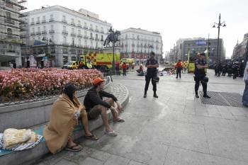  Varios policías vigilan a los 'indignados' acampados desde el 23 de julio en la Puerta del Sol, en Madrid, que han sido desalojados esta mañana por las fuerzas de seguridad, mientras los servicios municipales de limpieza retiran los residuos de la zona. 