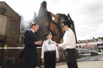  David Cameron habla con la superintendente del comando de la policía ante uno de los edificios quemados. (Foto: S. ROUSSEAU)
