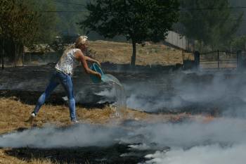 Una joven apaga el fuego con un cubo de agua, en el incendio de ayer de Vilar de Astrés. (Foto: JOSÉ PAZ)