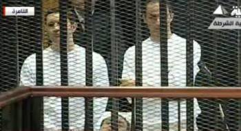 Imagen tomada del canal de televisión Al Arabiya de los dos hijos del ex presidente egipcio Hosni Mubarak Alaa (izq) y Gamal (dcha) mientras asisten desde una celda de la sala del tribunal a la segunda sesión de su juicio en El Cairo (Egipto) hoy, lunes 1
