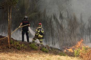 En la imagen, los bomberos intentan sofocar las llamas del incendio declarado ayer en Vilar de Astrés. (Foto: MARCOS ATRIO)