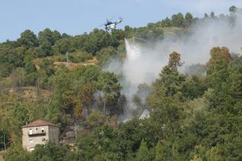 En la imagen, un helicóptero descarga agua sobre el fuego forestal que se declaró ayer en una zona de maleza en Cudeiro. (Foto: JOSÉ PAZ)