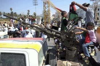 Dos menores, encaramados a un vehículo artillado de los rebeldes, en una calle de Trípoli. (Foto: HANNIBAL HANSCHKE)