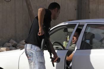 Un rebelde armado inspecciona un vehículo en una calle de Trípoli, (Foto: MOHAMED MESSARA)