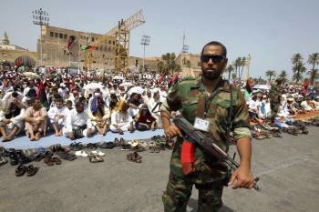 Un soldado rebelde vigila en una plaza de Trípoli durante la oración del viernes. (Foto: M. MESSARA)