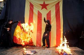 Unos encapuchados quemaron las banderas de España y Francia y una foto del Rey al acabar la manifestación independentista con motivo de la Diada que cada año discurre por el centro de Barcelona. (Foto: EFE)