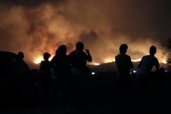 Vecinos de la localidad malagueña de Mijas, observan el incendio forestal declarado sobre las 20.30 horas de esta noche en el paraje de Entrerríos, obligando al desalojo preventivo de un centro de drogodependencia.  (Foto: EFE)