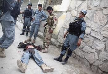 Policías afganos junto al cuerpo de un compañero muerto en el tiroteo con talibanes ayer en Kabul. (Foto: SABAWOON)