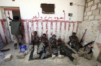 Rebeldes libios descansan armados en las inmediaciones de Bani Walid. (Foto: M. MESSARA)