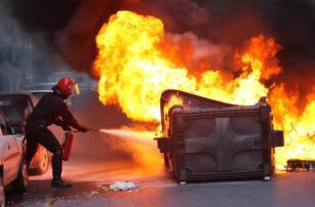  Un ertzaina sofoca el fuego en un contenedor durante el derribo del local juvenil Kukutza de Bilbao (Foto: EFE)