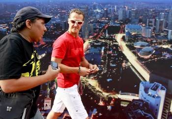 El piloto alemán de Fórmula uno Michael Schumacher (dcha), de Mercedes GP, conversa con un seguidor a su llegada a la primera sesión de entrenamientos en el circuito urbano de Marina Bay en Singapur  (Foto: EFE)