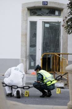 Un miembro de la Policia Judicial y un agente de la Guardia Civil examinan el suelo en la entrada de la sede de la Fundación Manuel Fraga, ubicada en la localidad lucense de Vilalba (Foto: EFE)