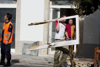 Varios operarios retiran la puerta de la sede de la Fundación Manuel Fraga, destrozada por la explosion. (Foto: ELISEO TRIGO)