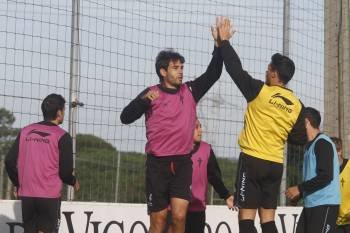 Borja Oubiña y Carlos Bellvís chocan sus manos durante el entrenamiento celebrado ayer en A Madroa.