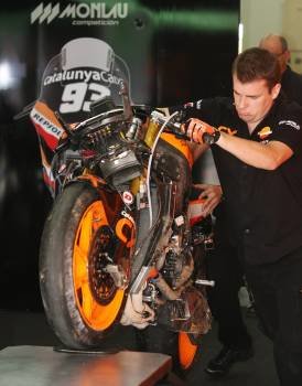 Un mecánico mueve la moto accidentada de Márquez. (Foto: AZHAR RAHIM)
