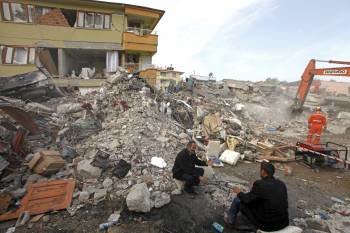 Dos hombres están junto a los escombros de un edificio, donde trabajan los equipos de rescate. (Foto: TOLGA BOZOGLU)