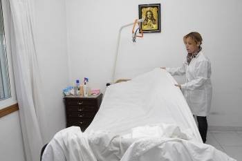 Una auxiliar prepara la cama de un paciente.